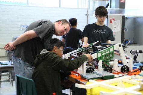 Teacher David Black shows senior Joshua Valerio how to wire parts of the robot together. During prior years’ training sessions, Valerio learned various skills like wiring and prototyping.   