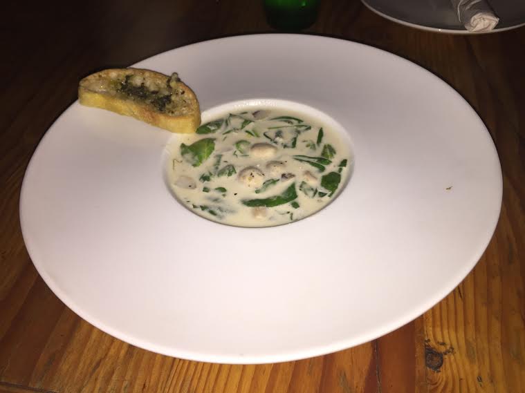 The cream of spinach is a delicious soup that is served with garlic bread to add flavor. 
