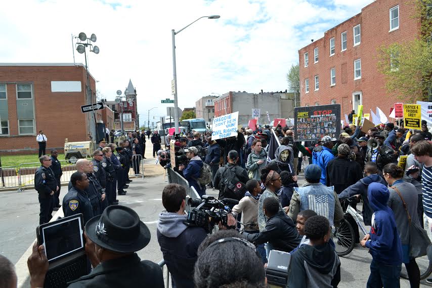 Civilians of Baltimore holding up posters, and protesting against the police officials of Baltimore. 
