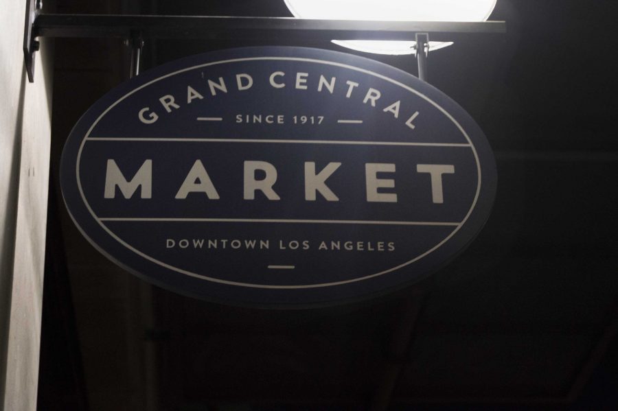 The Grand Central Market sign that is posted outside the entrance. The market sells food from many different cuisines and cultures. 
