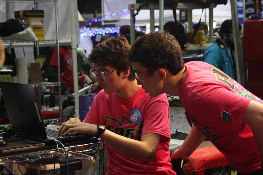 Torres, the teams programmer, fixes the robots code as Luke looks on.