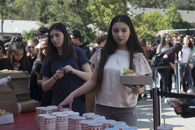  Junior Lauren Muradian (right) finally gets her In-N-Out burger and drink after waiting in a long line with her friend, junior Carmen Hovhannisyan (left).