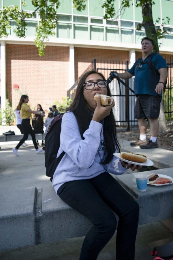 Senior Sangam Sharma grabs a freshly grilled hot dog from Mr. Pruitt at the senior barbecue.