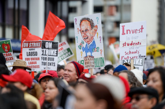 Teachers and supporters hold up signs to get their message out to the community. 