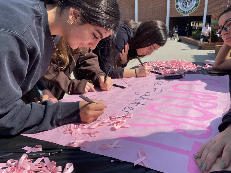Students at the ASB station signing the poster with positive messages for Breast Cancer patients. 
