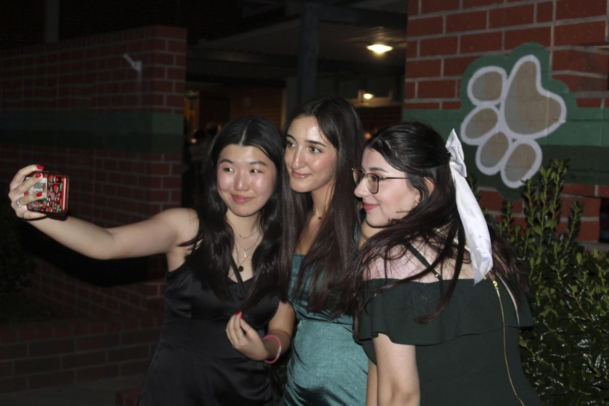 Seniors Hailey Wong, Gabrielle Najarian, and Lori Daghlian taking selfies at Homecoming.
