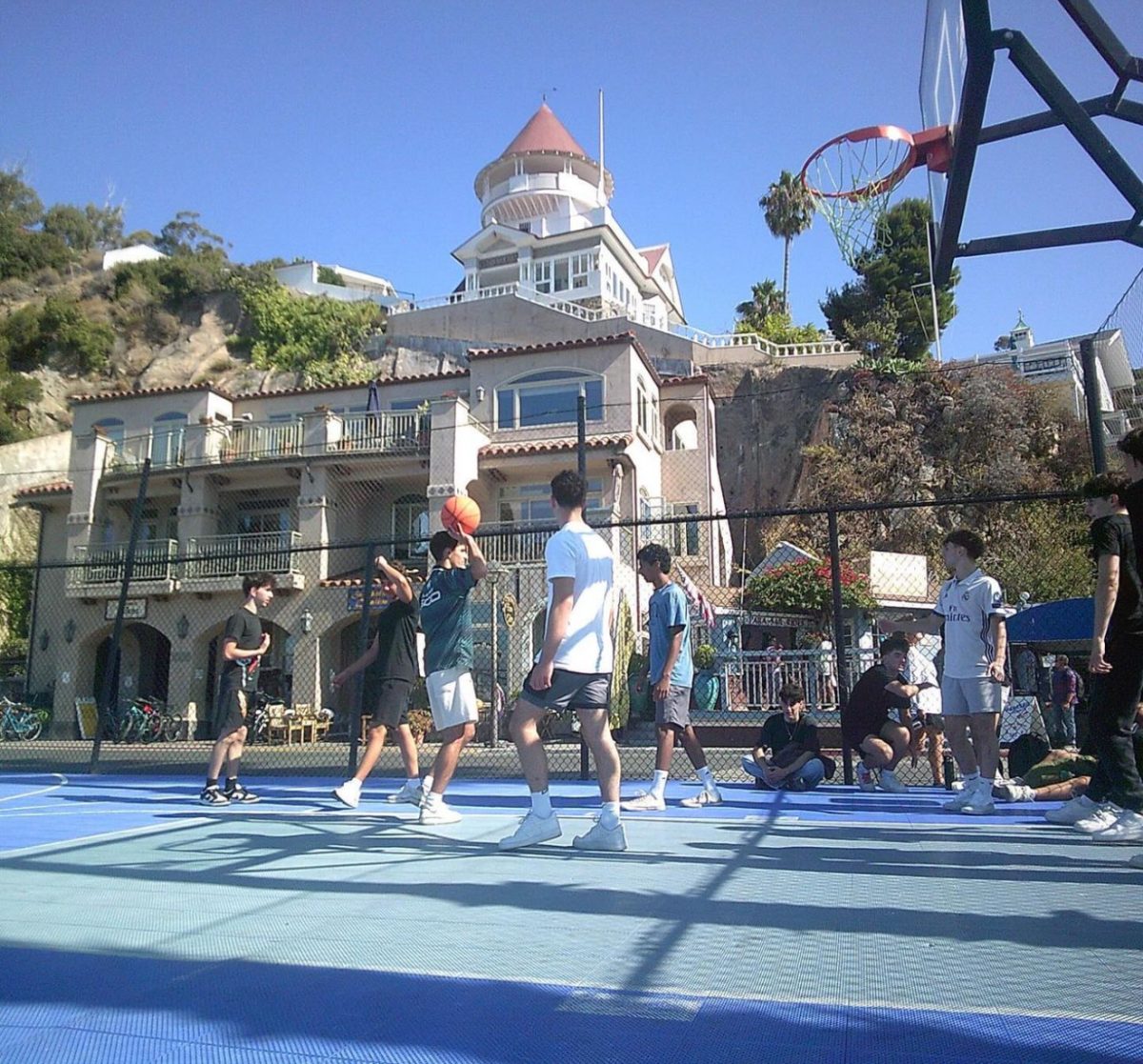 Grigor Tamamyan, Vincent Kalachian, Dante Araratyan, Hrag Khatcherian, Noah Kurien, Antony Karamanian, and David Aydenjian play a game of basketball with a scenic view of the Catalina architecture.