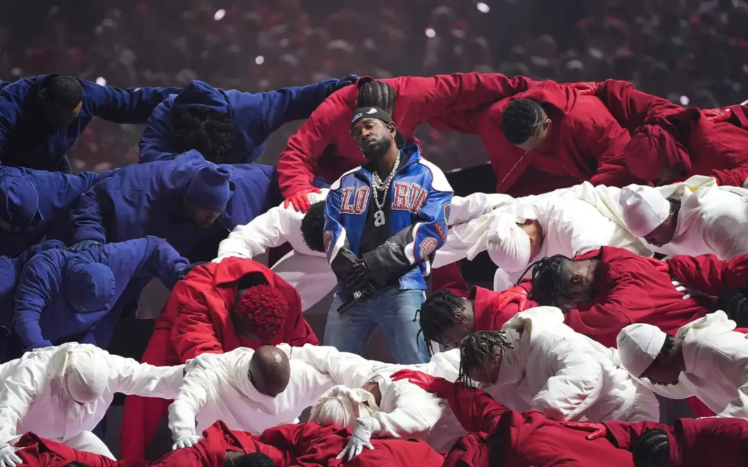 Image of rapper Kendrick Lamar surrounded by his halftime show performers who have formed an American flag around him.
