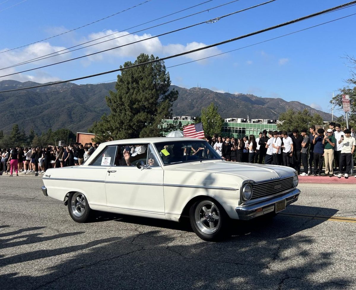 Students watch as a vintage car passes during the motorcade.