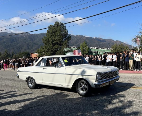 Students watch as a vintage car passes during the motorcade.