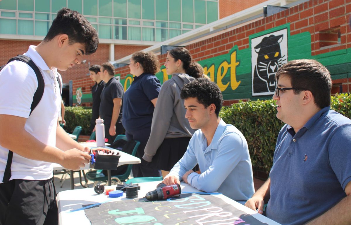 Seniors Andre Gasparian and Vahe Amirkhanian showcasing 3-D printing club to Niko Ter-Oganesyan.