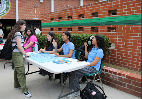Seniors Mehreen Azad, Sheenamarie Tanghal, and Karina Hartenyan showcasing UNICEF Club to senior Lilia Hartonian