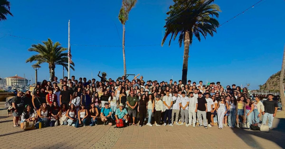 The Class of 2026 pose for a photo in front of the beach.