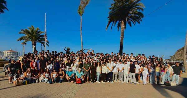 The Class of 2026 pose for a photo in front of the beach.